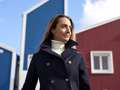 Femme devant le bâtiment bleu et rouge de Dalmard Marine sur le port de Paimpol en caban